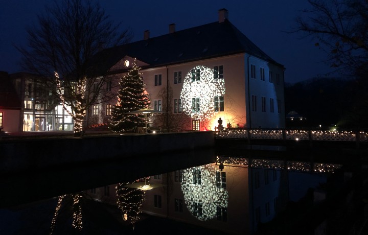 Haupthaus Schloss Benkhausen mit winterlicher Beleuchtung und Reflektionen im Schlossgraben